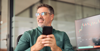 Business professional holding a mobile phone and looking ahead in an office setting
